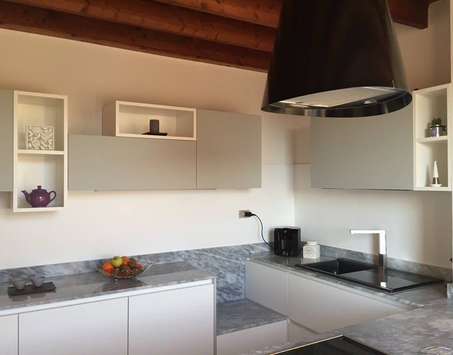 Cucina a Usago: parete attrezzata con mensole a giorno e soffitto in legno